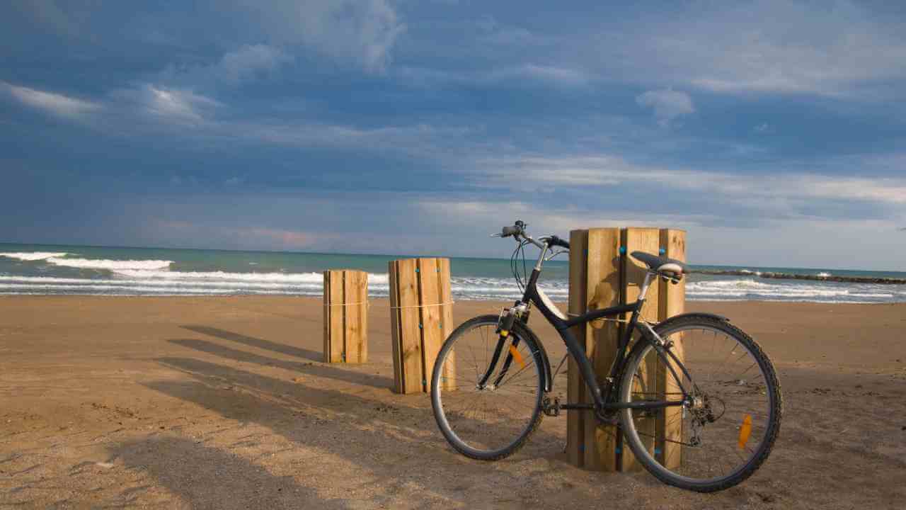 a bicycle is leaning against a wooden post on the beach