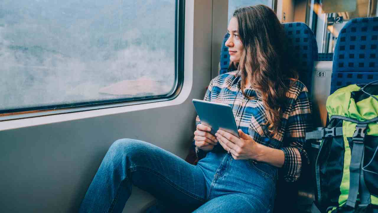 A person sitting on a train looking at their tablet