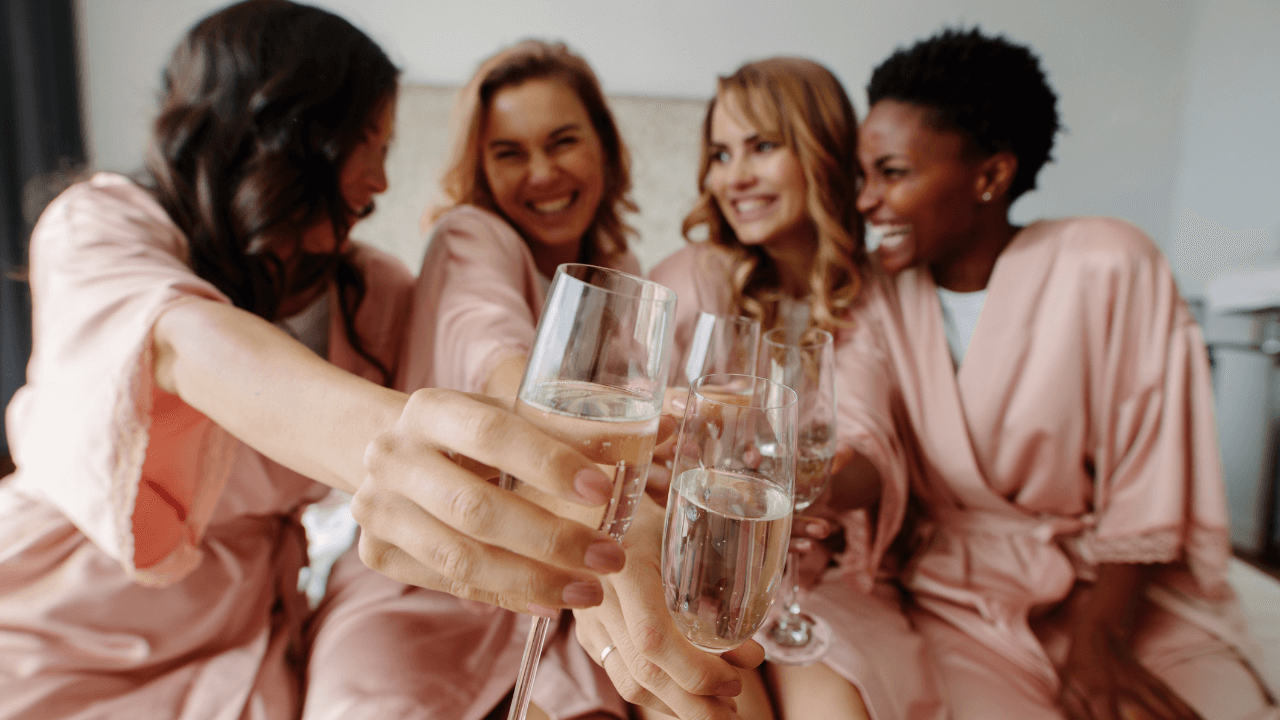 a group of individuals in pink robes toasting champagne