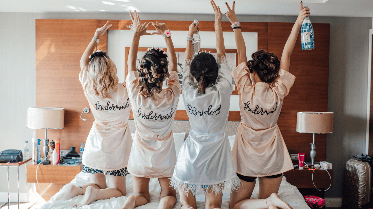 Four bridesmaids in robes sitting on a bed