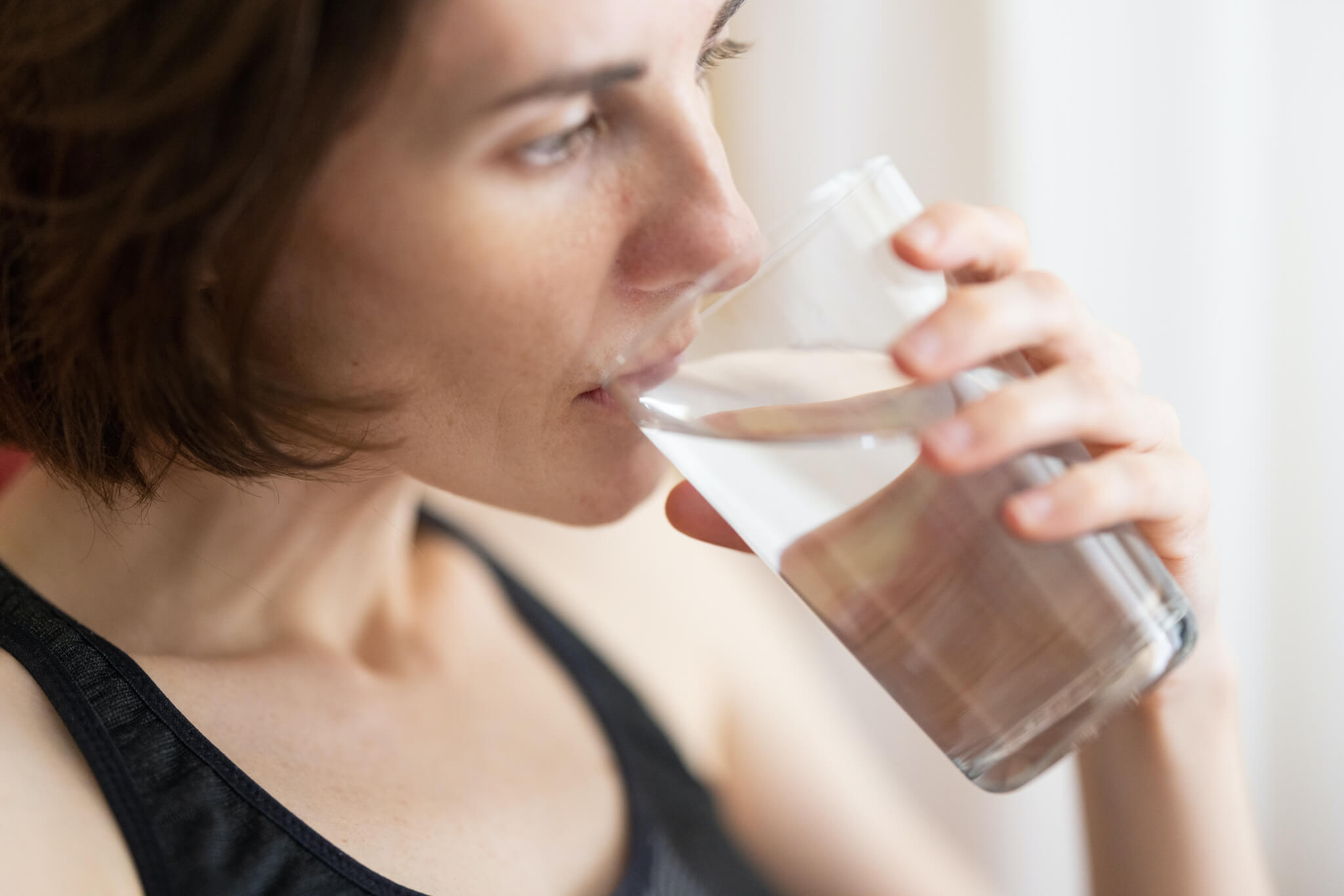 a woman drinking a glass of fresh water