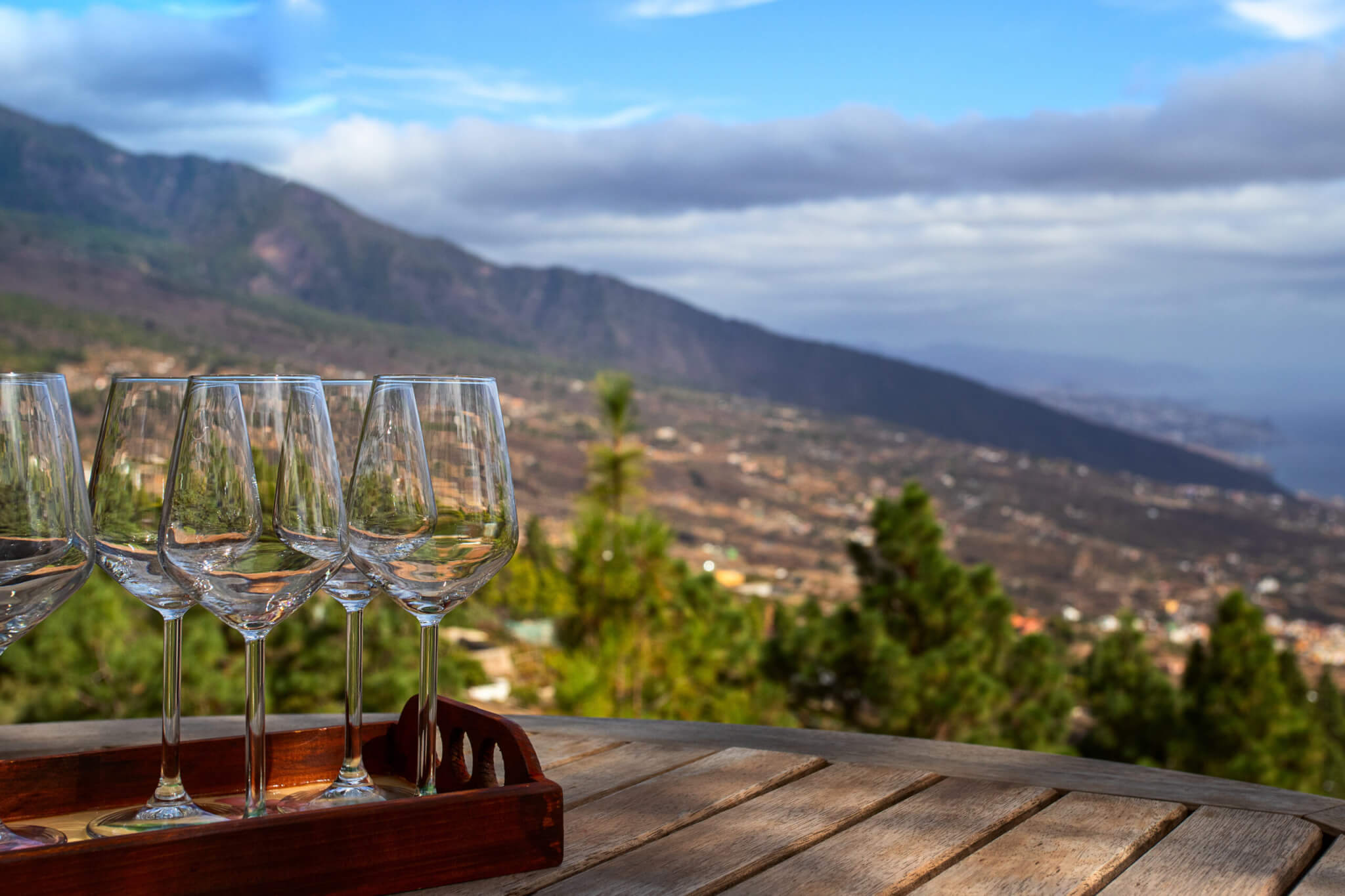 Empty wine glasses on wooden table on vineyards land in the mountains. Wine tasting experience concept.