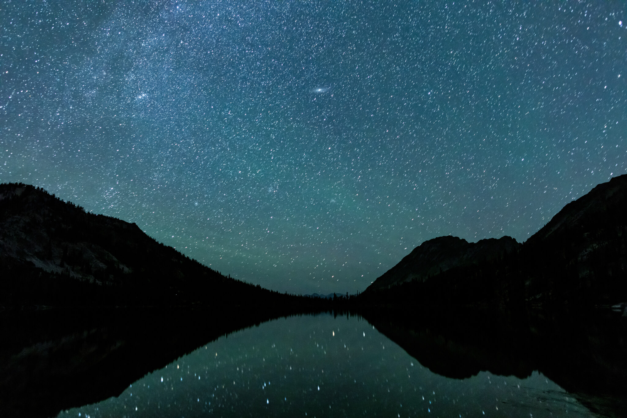 Toxaway Lake, located in Idaho’s Sawtooth Wilderness seen on a summer night with many stars in the sky and reflected in the water's surface.