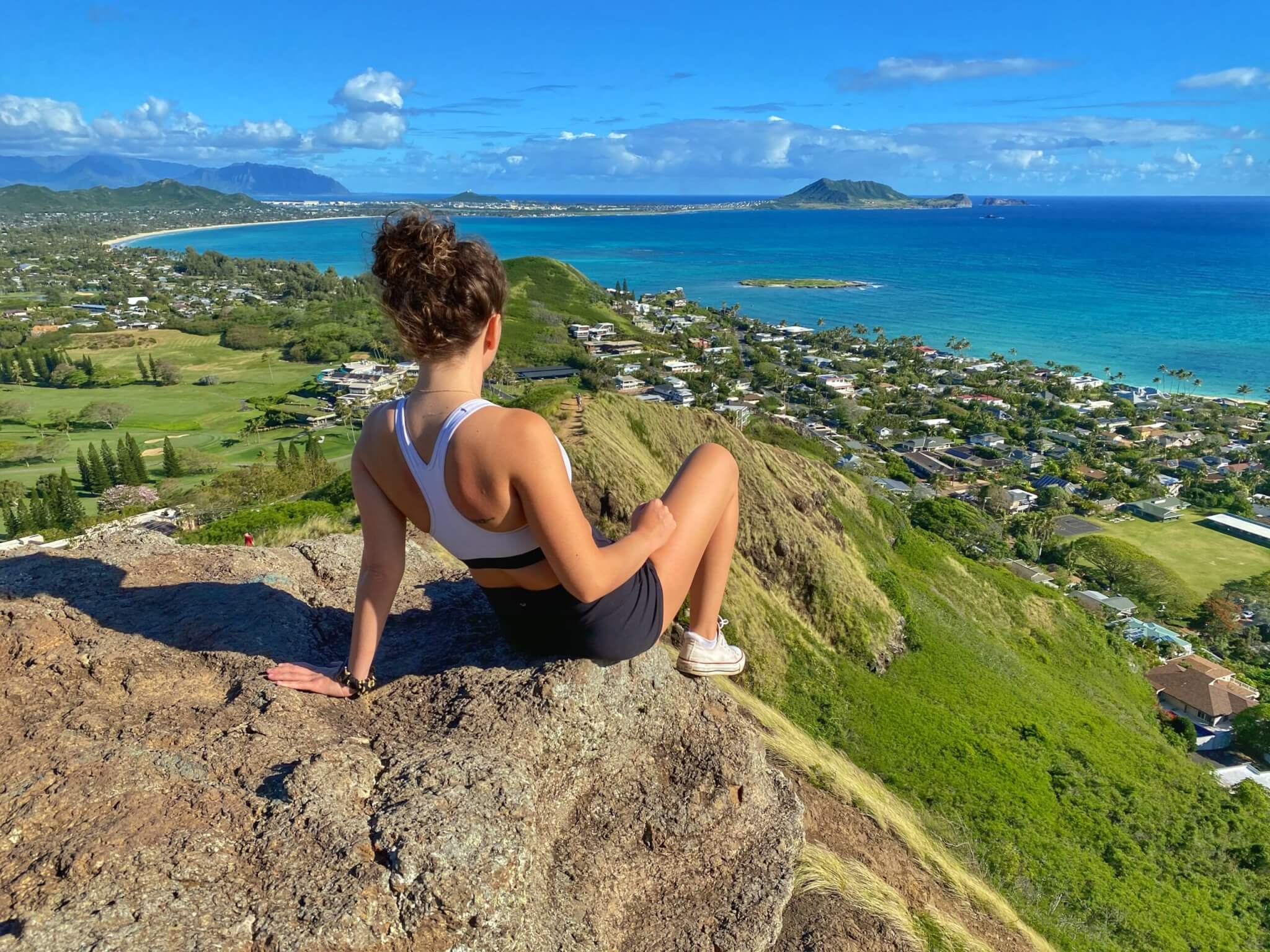 woman on the rocks overlooking the ocean and city