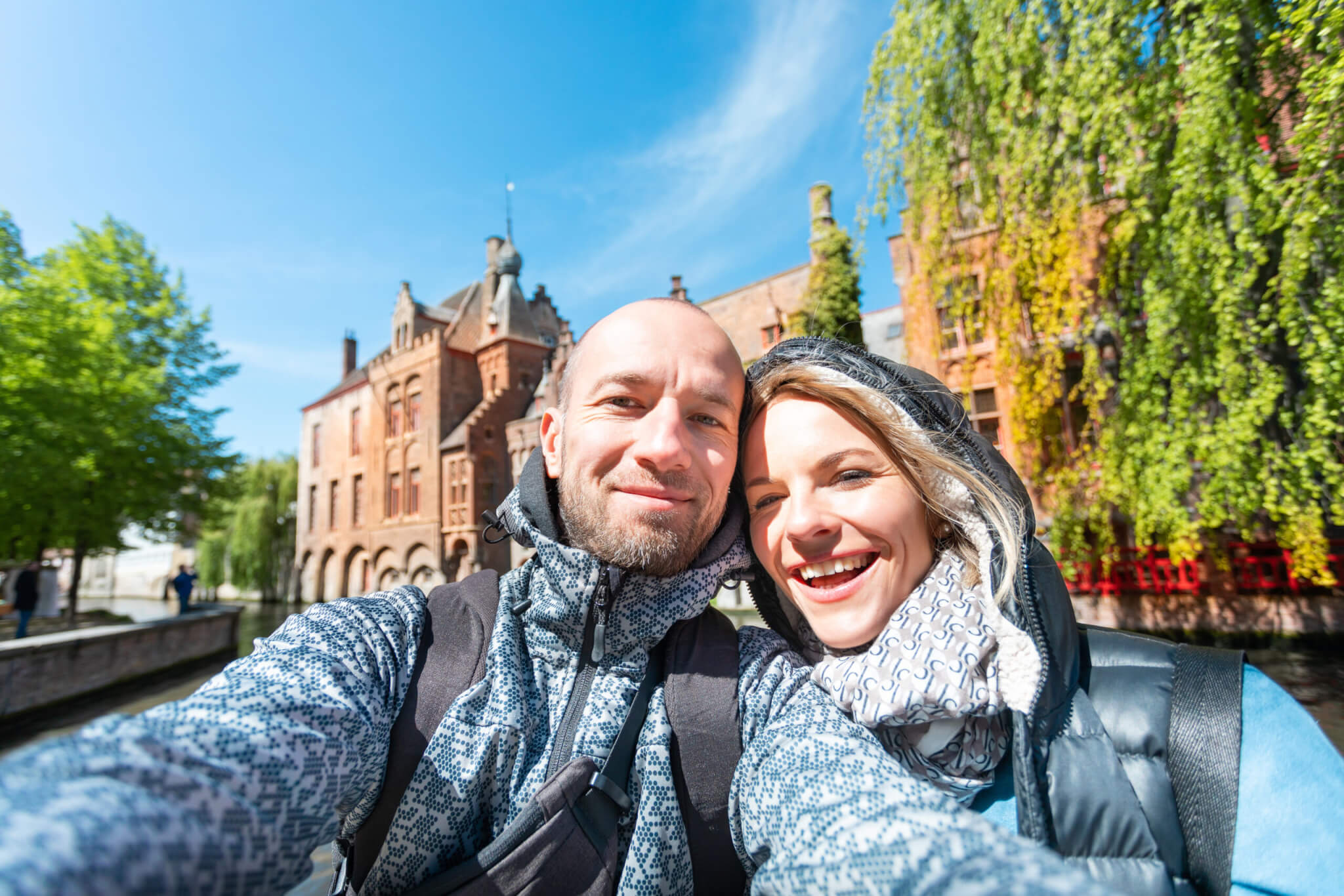 Young couple takes selfie pictures on the main street of Bruges, Belgium.