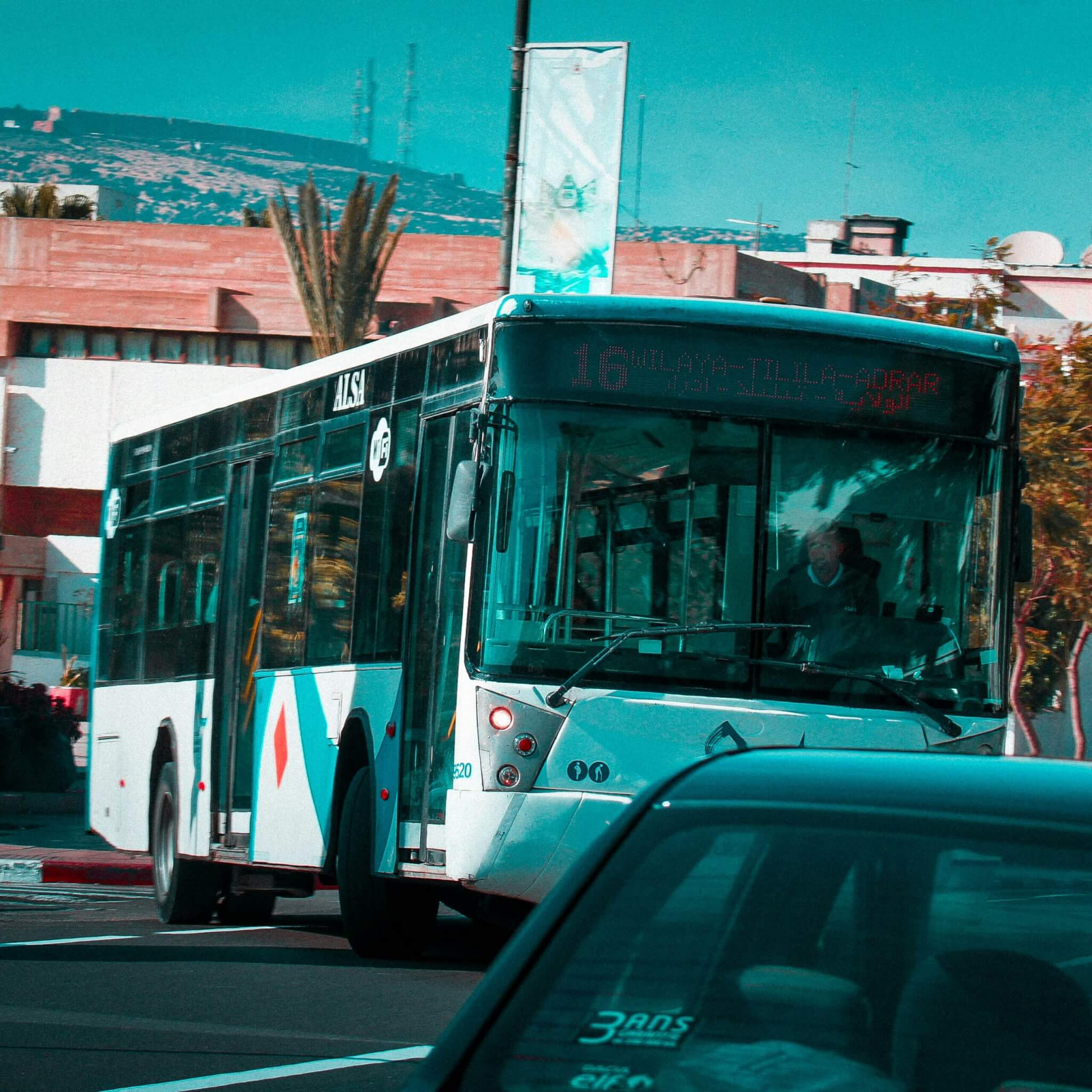 a city bus driving down a street next to a car