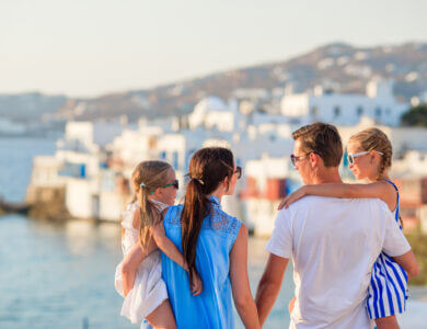 Family vacation in Europe. Parents and kids on Little Venice background on Mykonos Island, in Greece