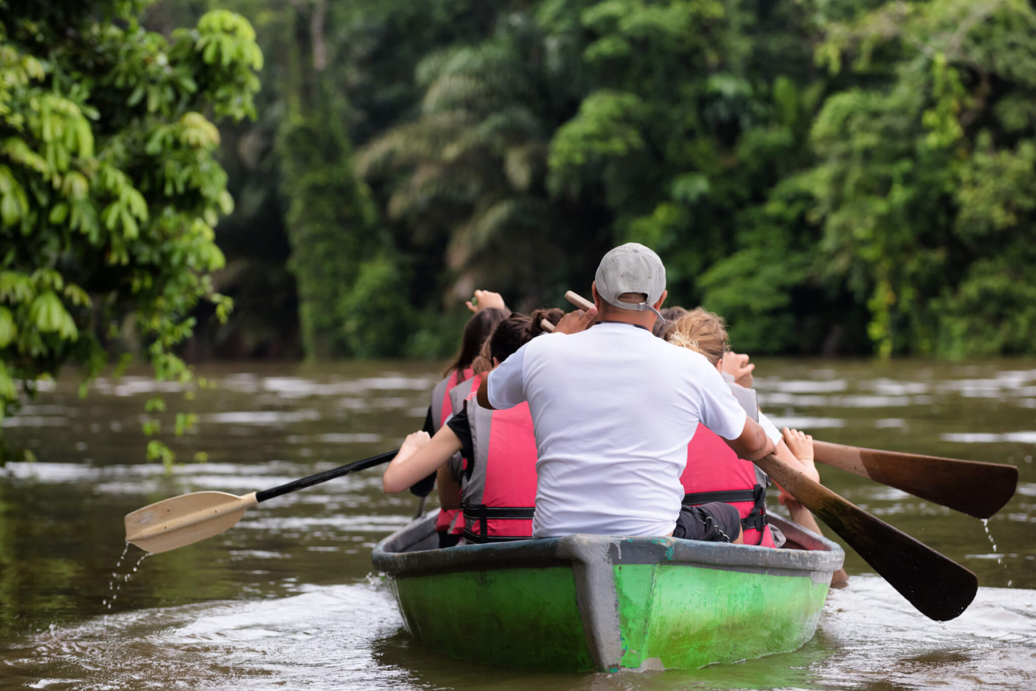 People exploring a wild nature area by rowing boat. Ecotourism concept. Tortuguero national park. Costa Rica.