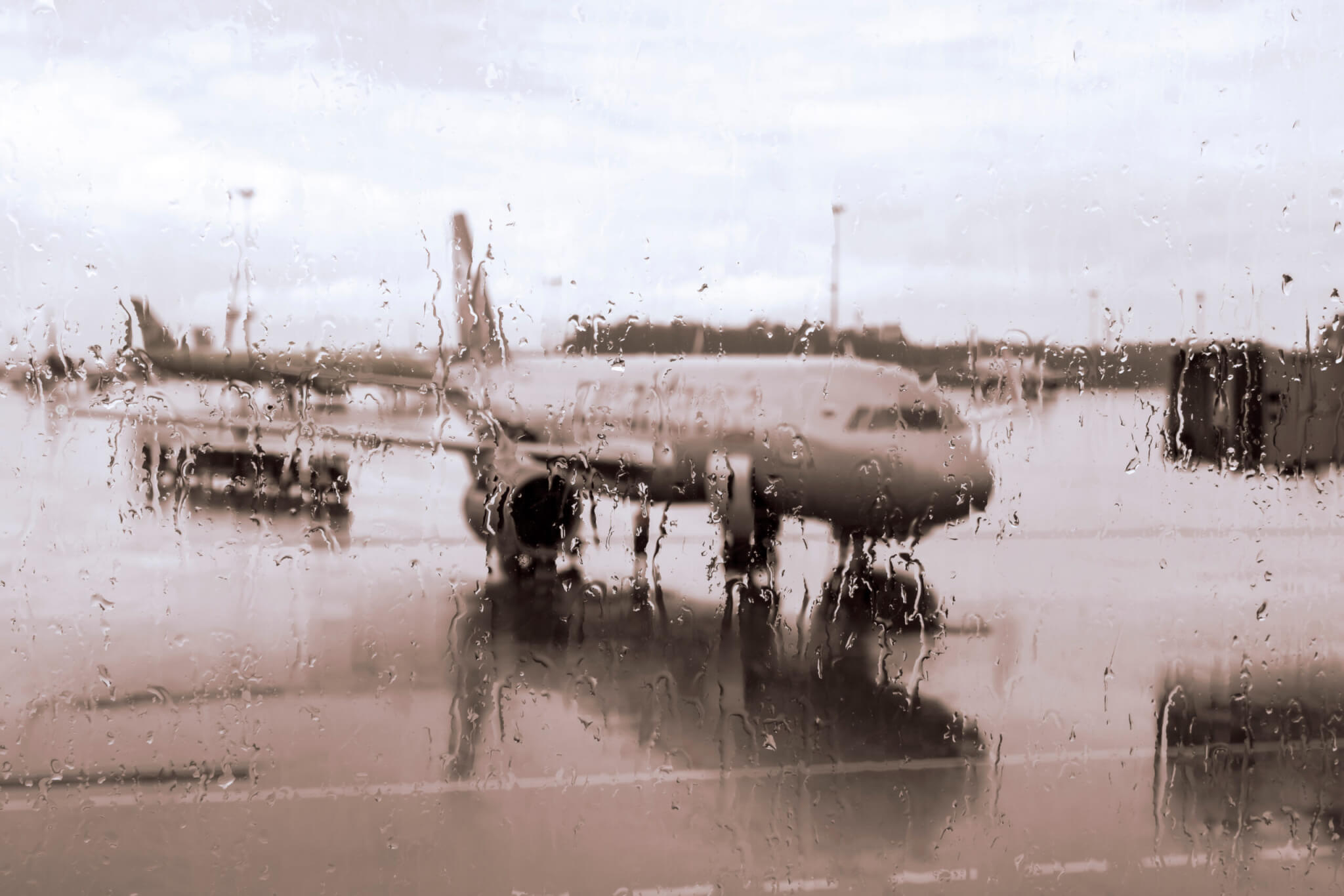 Unfocused view of the plane through the airport window, with raindrops.