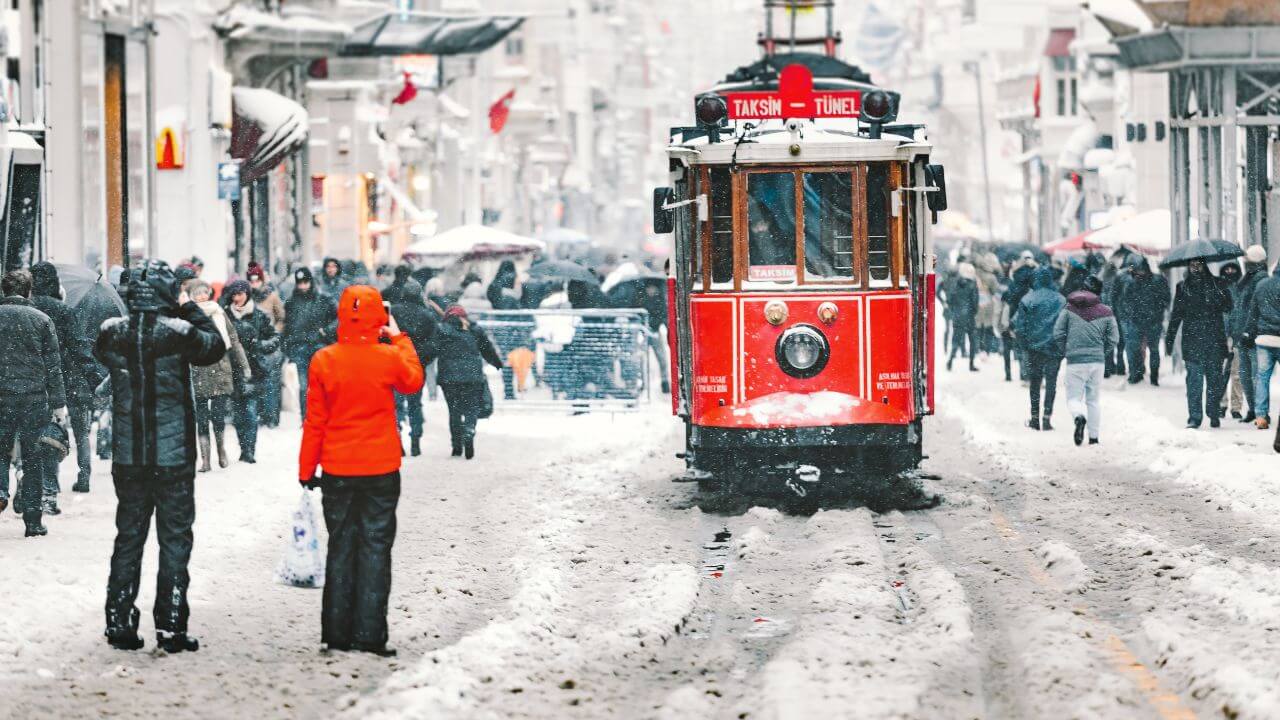 people walking down a snowy street with a trolley car in the background