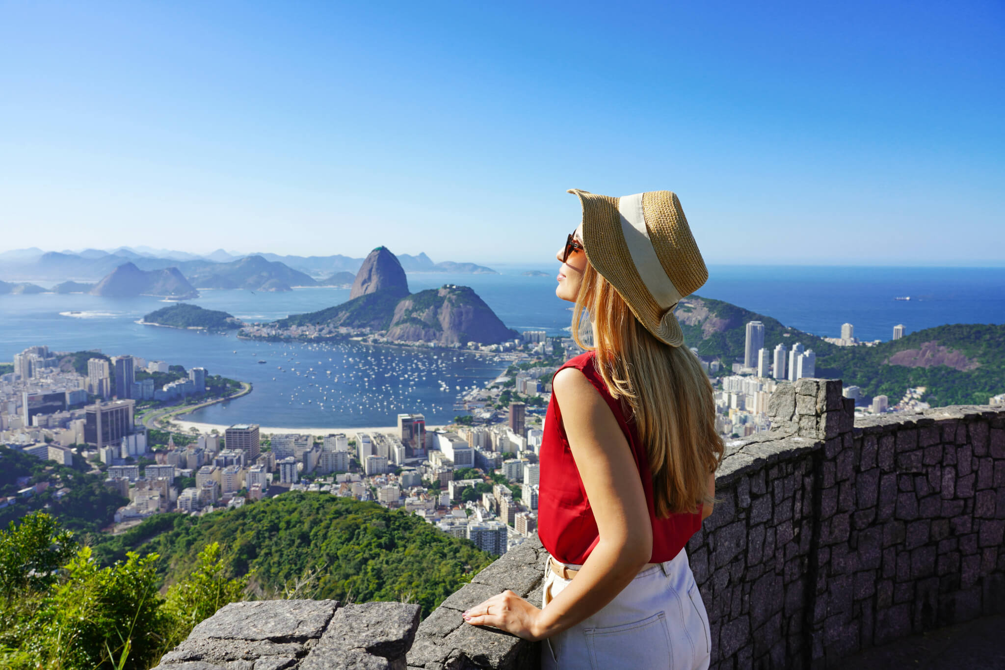 Fashion tourist woman on terrace in Rio de Janeiro with the famous Guanabara bay and the cityscape of Rio de Janerio, Brazil