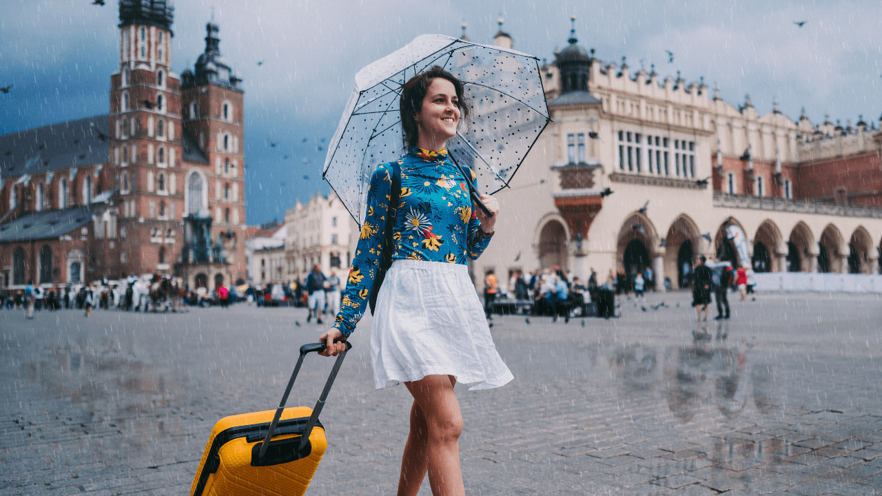 happy girl traveler in the rain with a suitcase getting ready to explore her new destination 