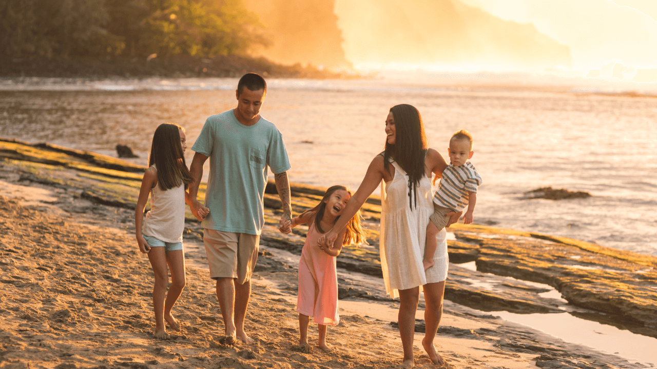 happy family of 5 walking along the beach during sunset while being on vacation 