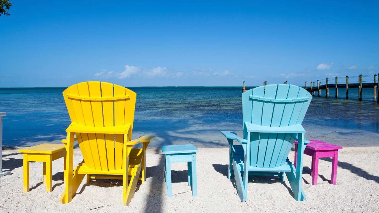 yellow and blue beach chairs on the sand facing the ocean