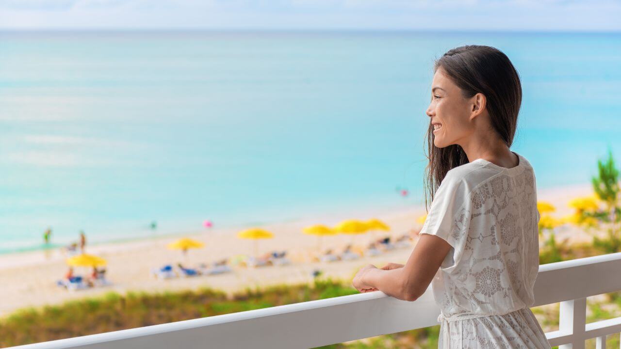 woman looking out her balcony towards the beach and ocean 