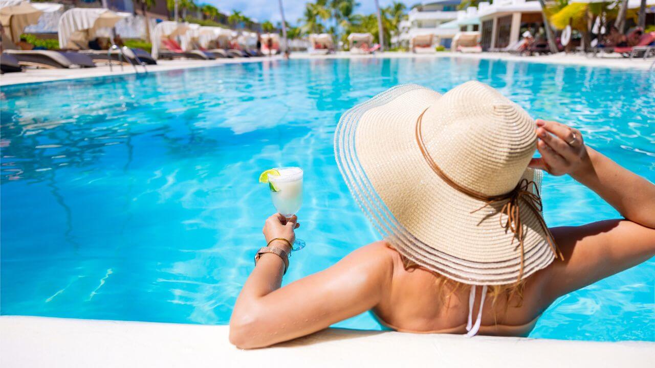 woman with a beach hat on and frozen cocktail in her hand in the pool