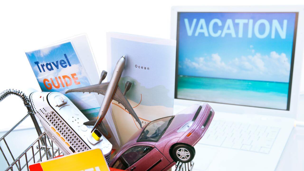 vacation on a laptop with a toy cruise ship, plane, car, travel guide and map in a shopping cartacting as a 'package'