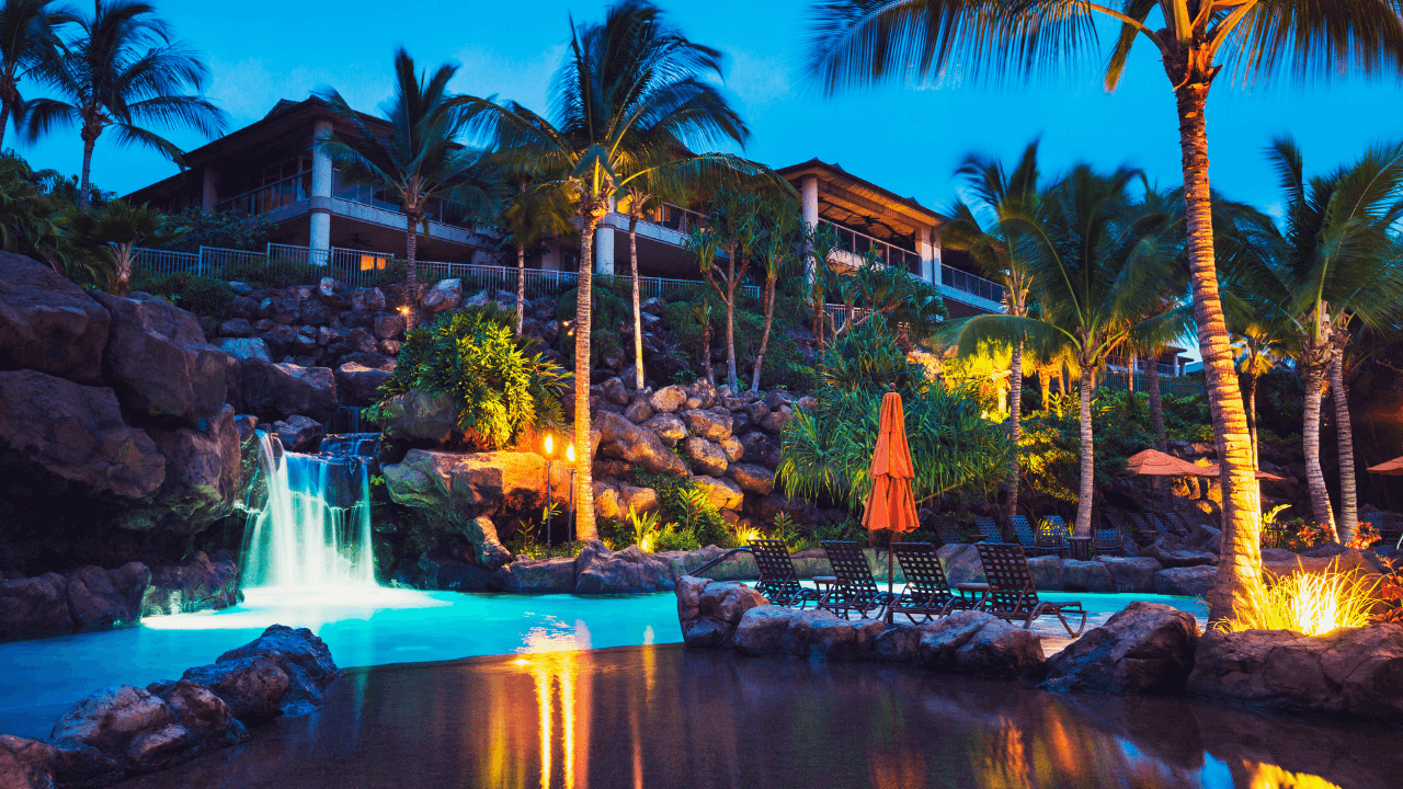 tropical resort at nightime  with a waterfall going into the pool 