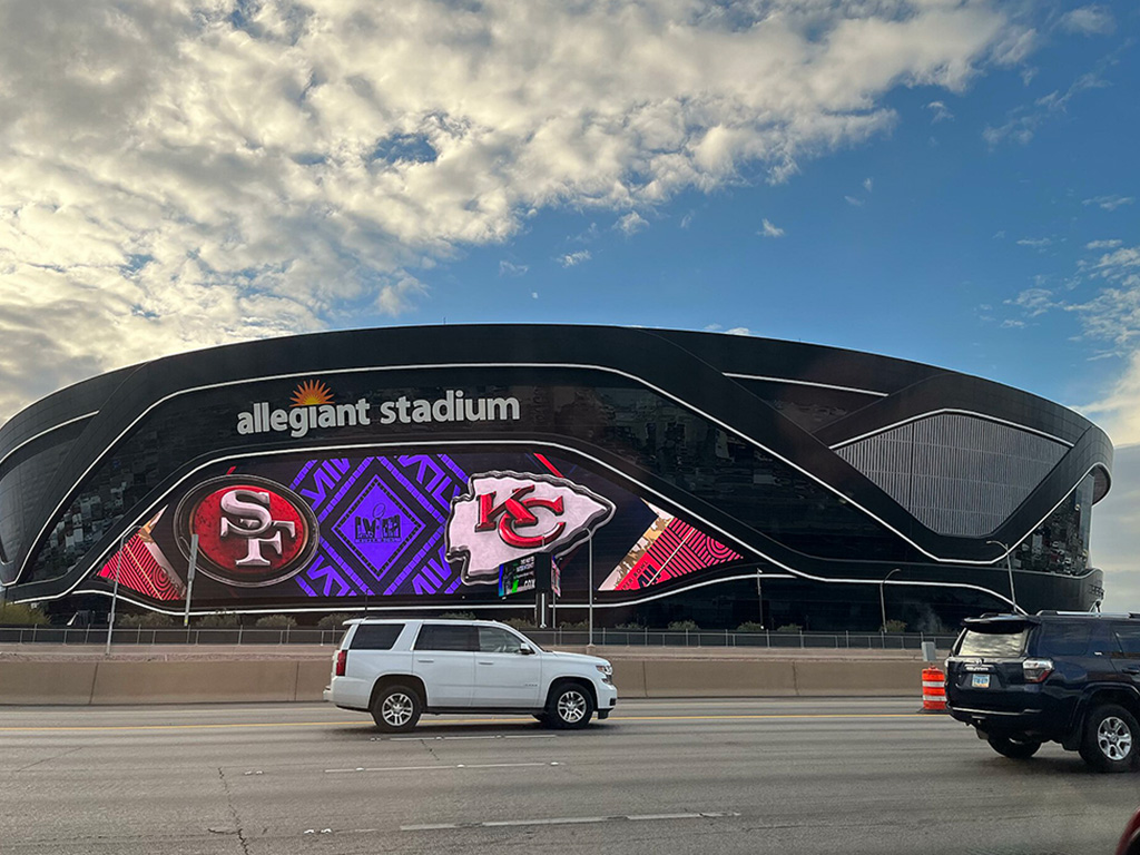 Allegiant Stadium, view from the northbound lane of Interstate 15. The stadium's exterior video board displays an advertisement for the upcoming LVIII, which will be hosted at the stadium the following week.