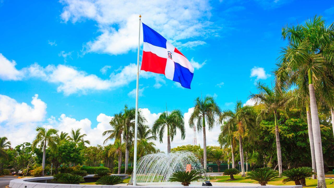 dominican republic flag with  a fountain and palm trees in the back 