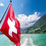 switzerland flag with water and mountains in the background