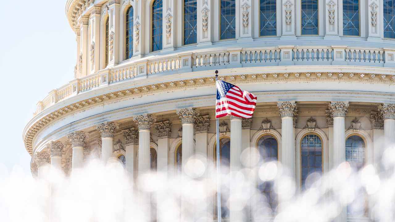close up picture of the capital building with the american flag blowing in the wind