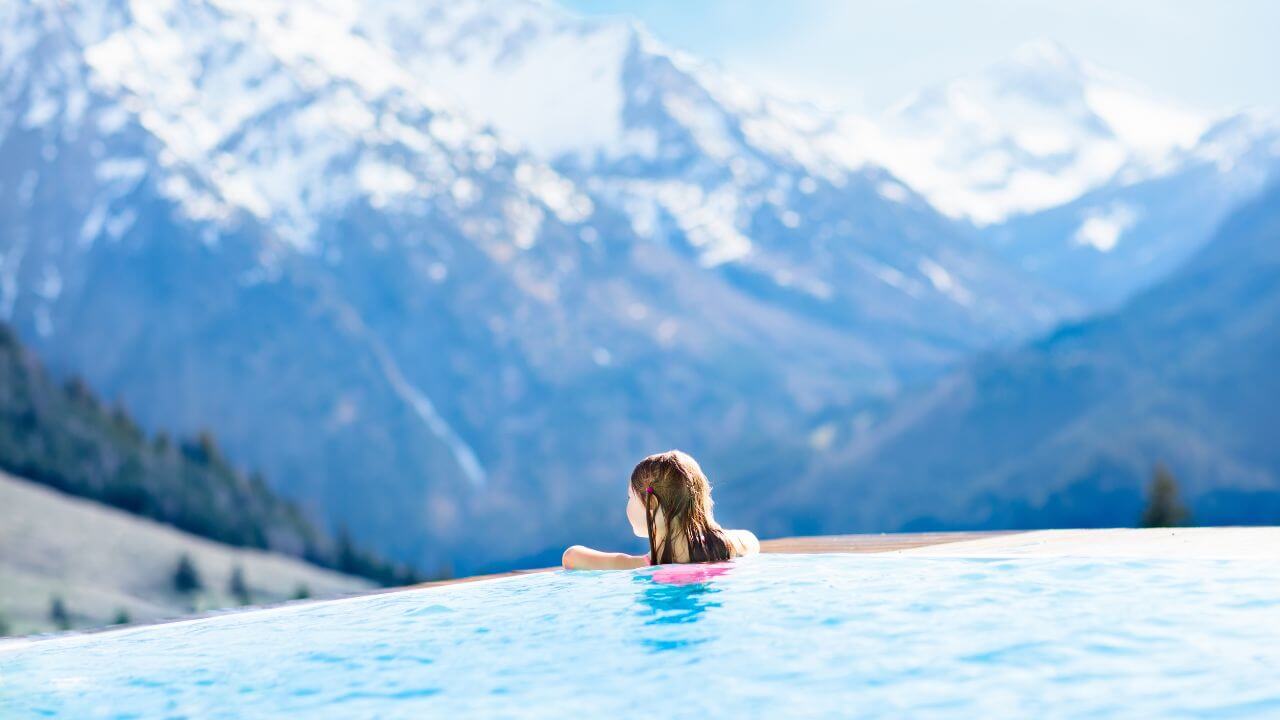 person in infinity pool overlooking the swiss alps