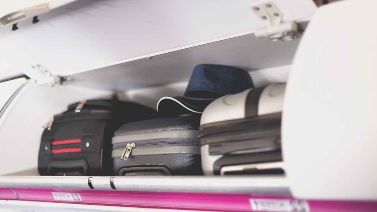 luggage in over head compartment on plane