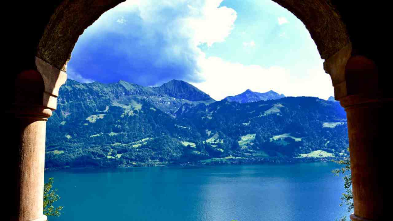 a view of a lake and mountains through an archway