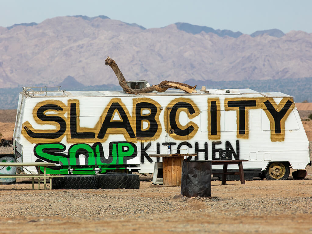 The Famous Slab City, California, where an independent community has grown to take over the Dunlap Army Base Site looking at a trailer painted as a soup kitchen