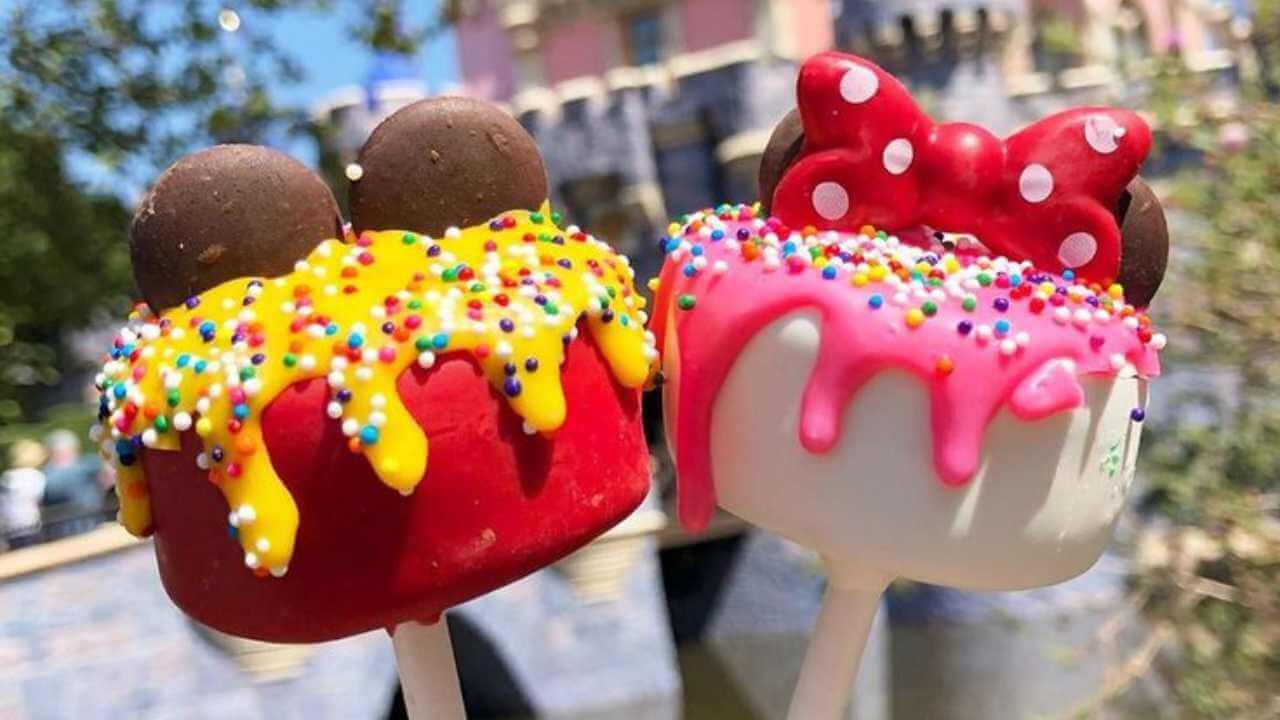 red and white cake pops with mickey and minnie ears on top in front of disney castle