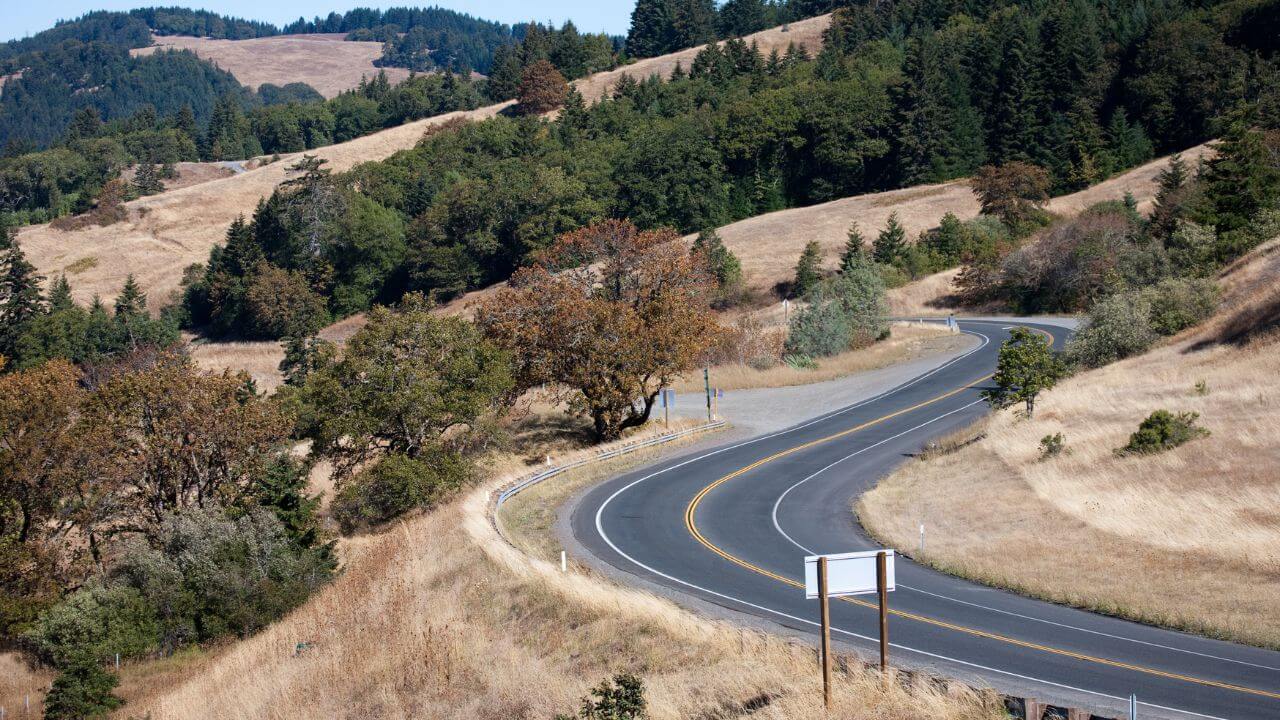 a winding road with trees and hills in the background