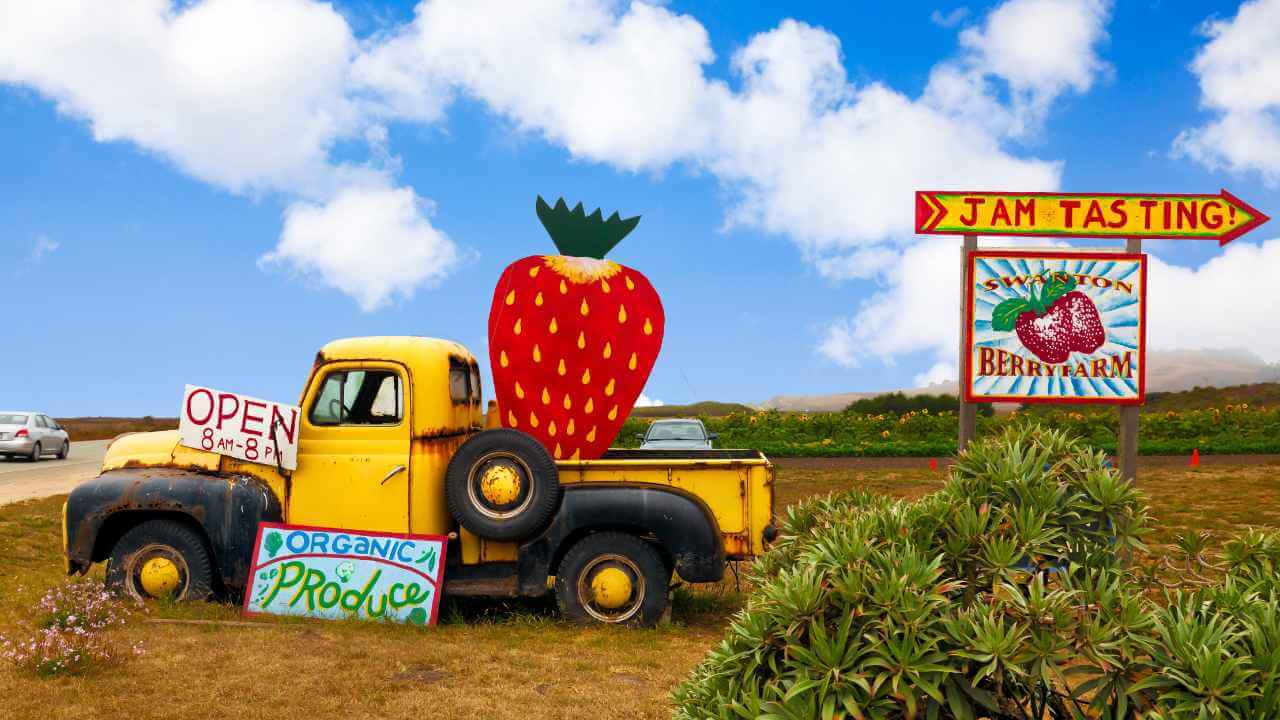 yellow truck with strawberry on top of it in a field