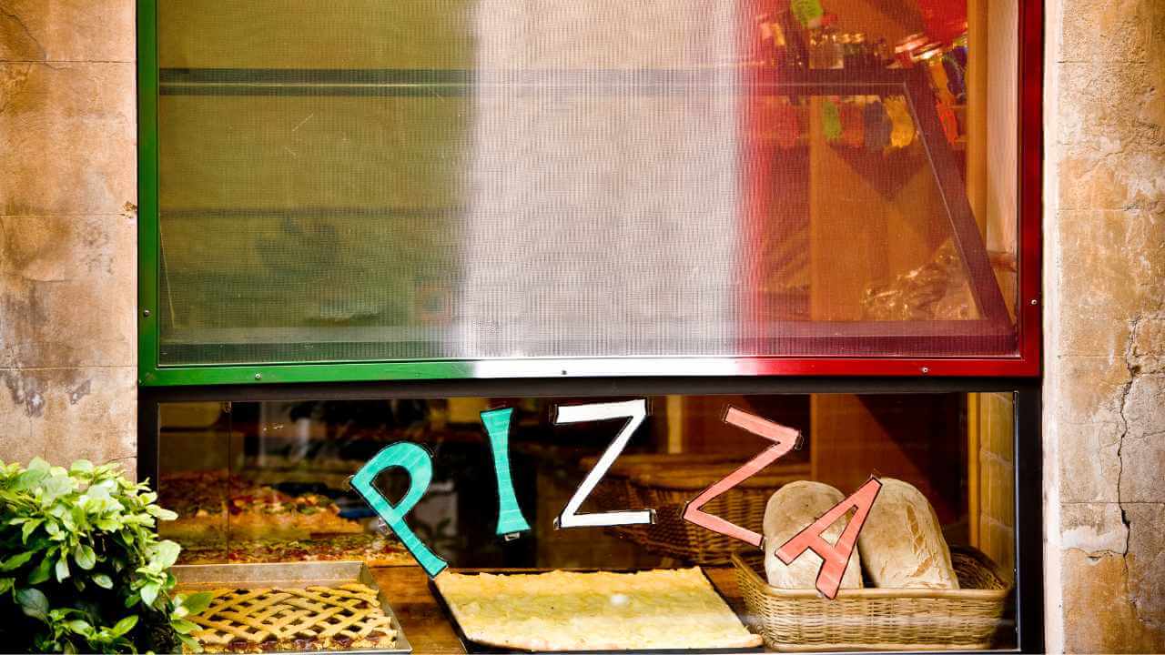 pizza written on a window to a pizza shop in rome