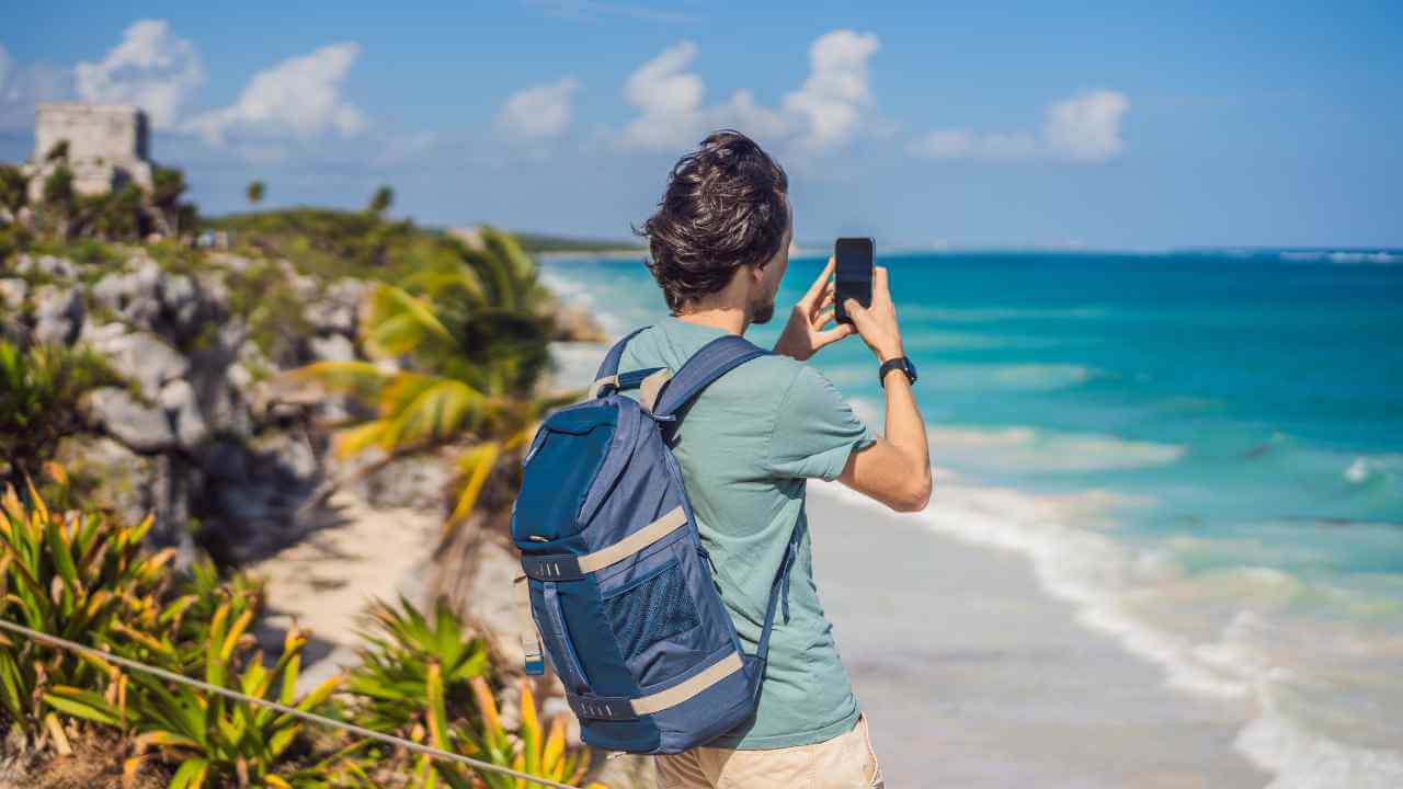 male tourist taking picture at the beach in tulum