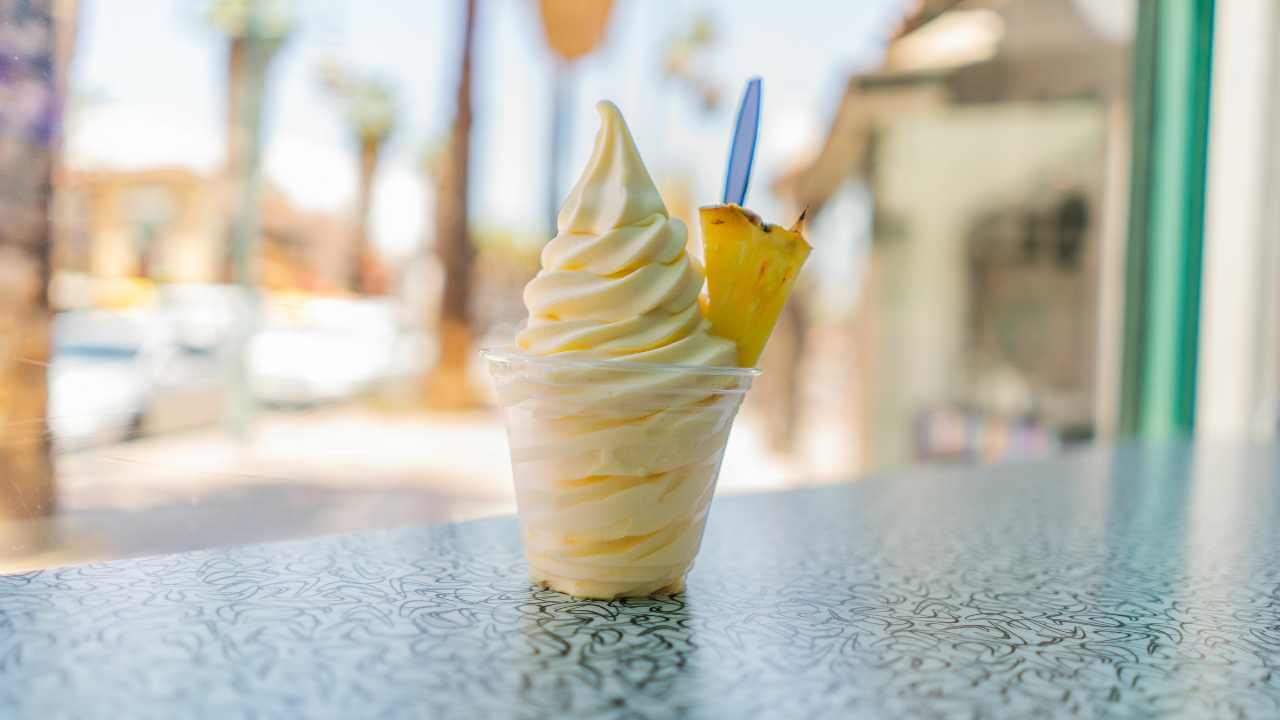 pineapple soft serve in a cup with a pineapple chunk as a garnish