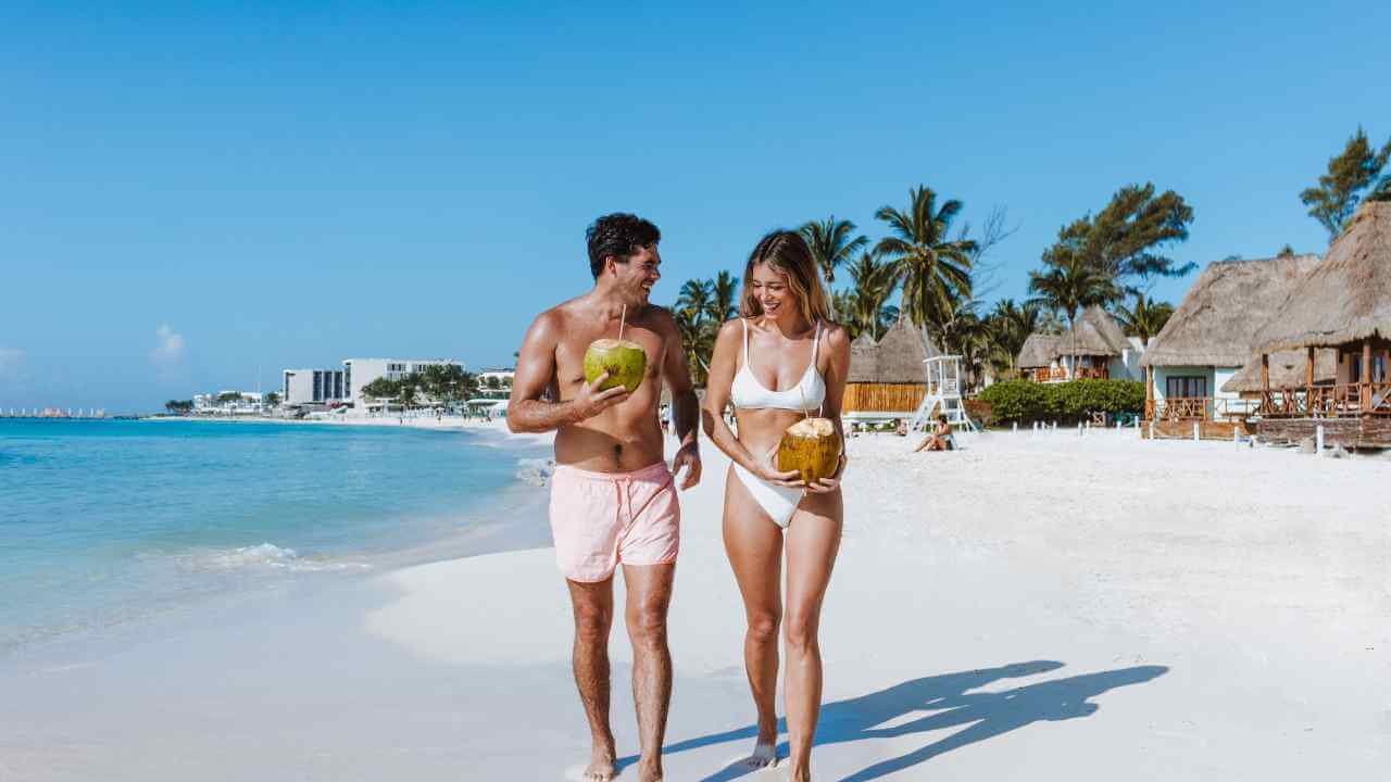 man and woman walking on the beach in tulum 