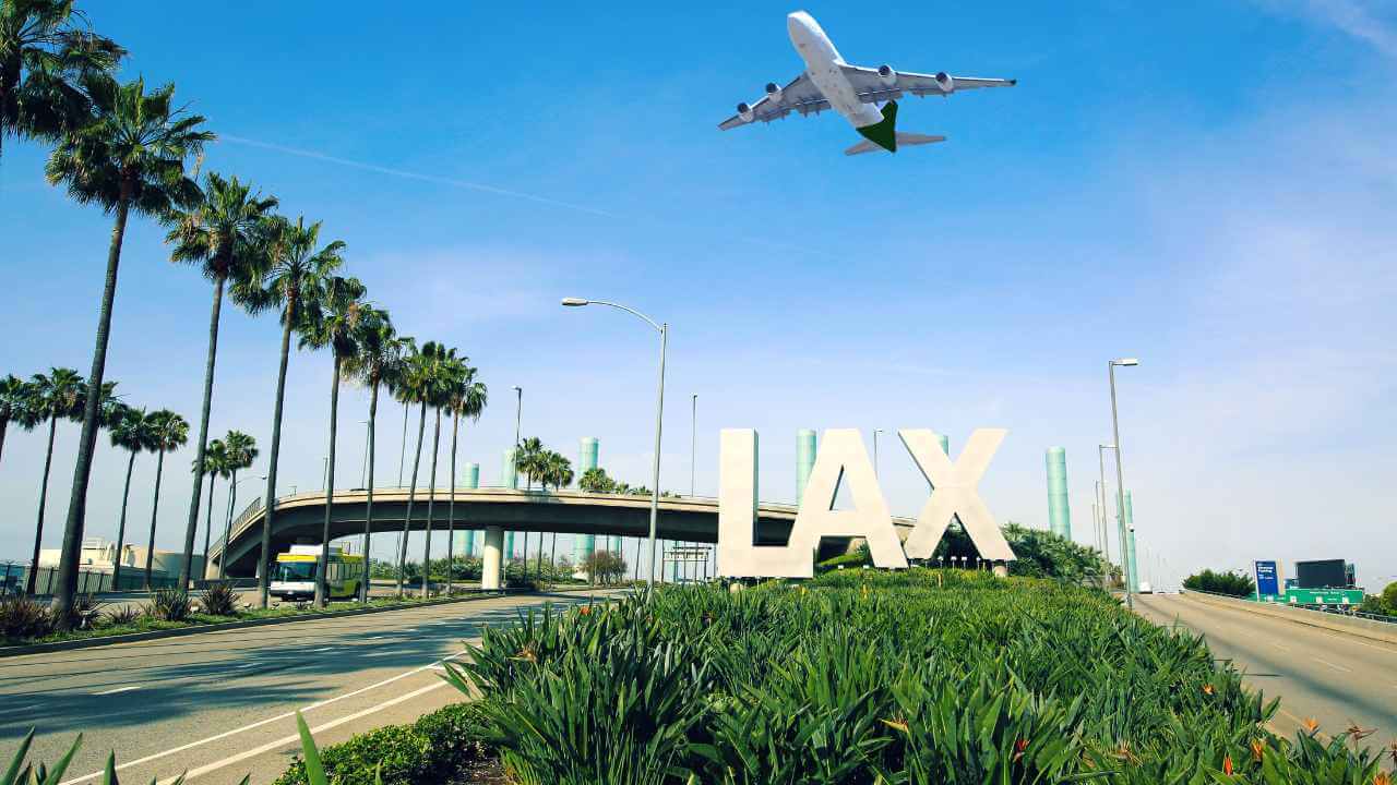 lax airport sign with a plane flying overhead