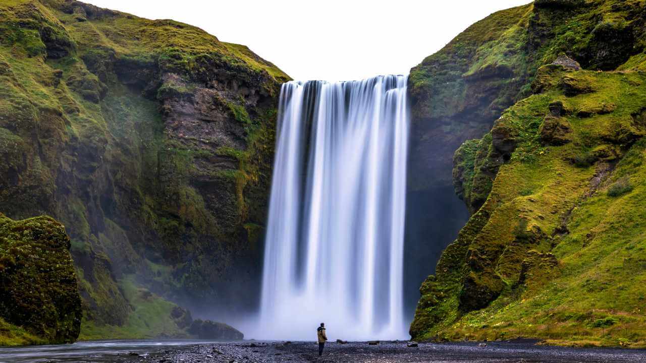person looking at a waterfall in iceland