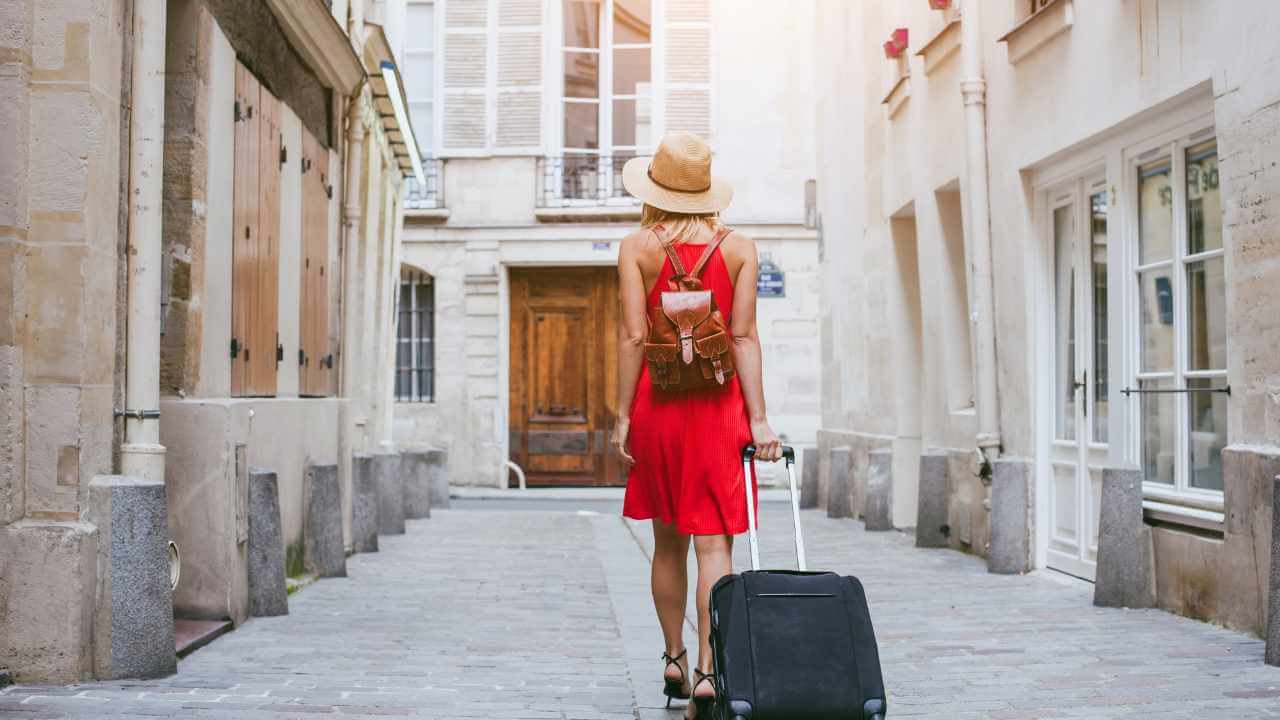 travel background, woman tourist walking with suitcase on the street in european city, tourism in Europe