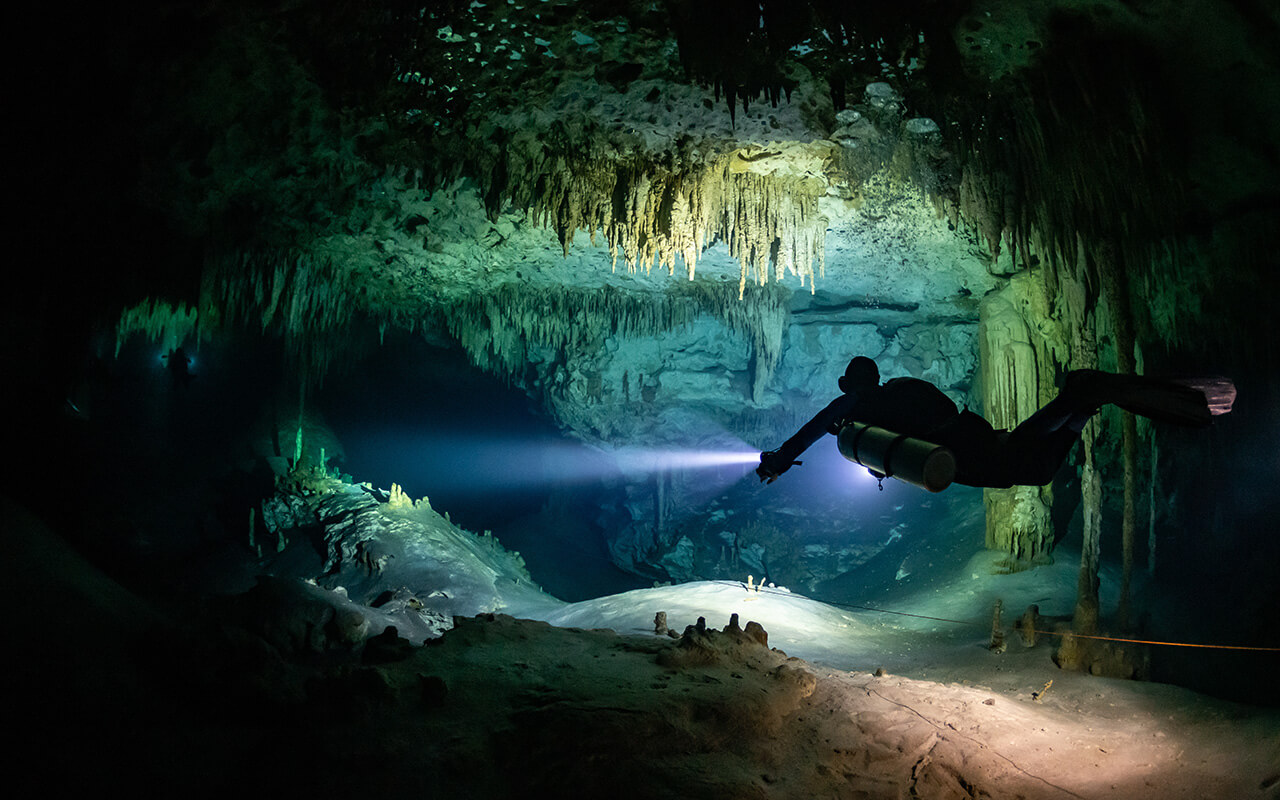 cave diver instructor leading a group of divers in a mexican cenote underwater