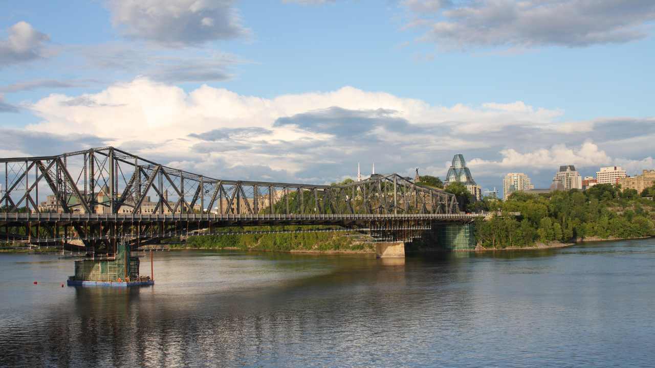 a bridge spanning over a river with a city in the background