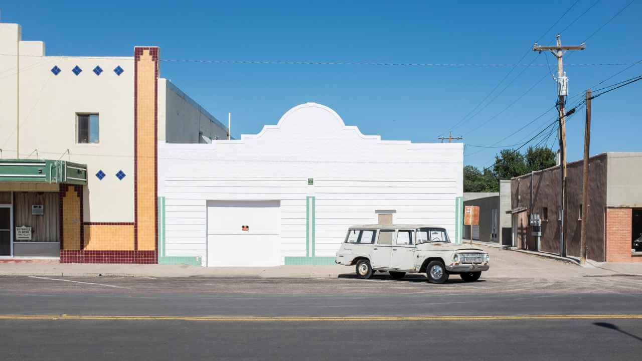 an old car is parked in front of an old building