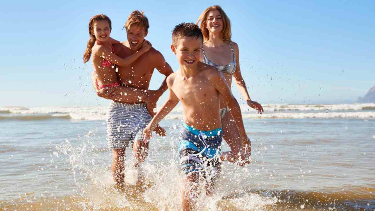 a family running through the water at the beach