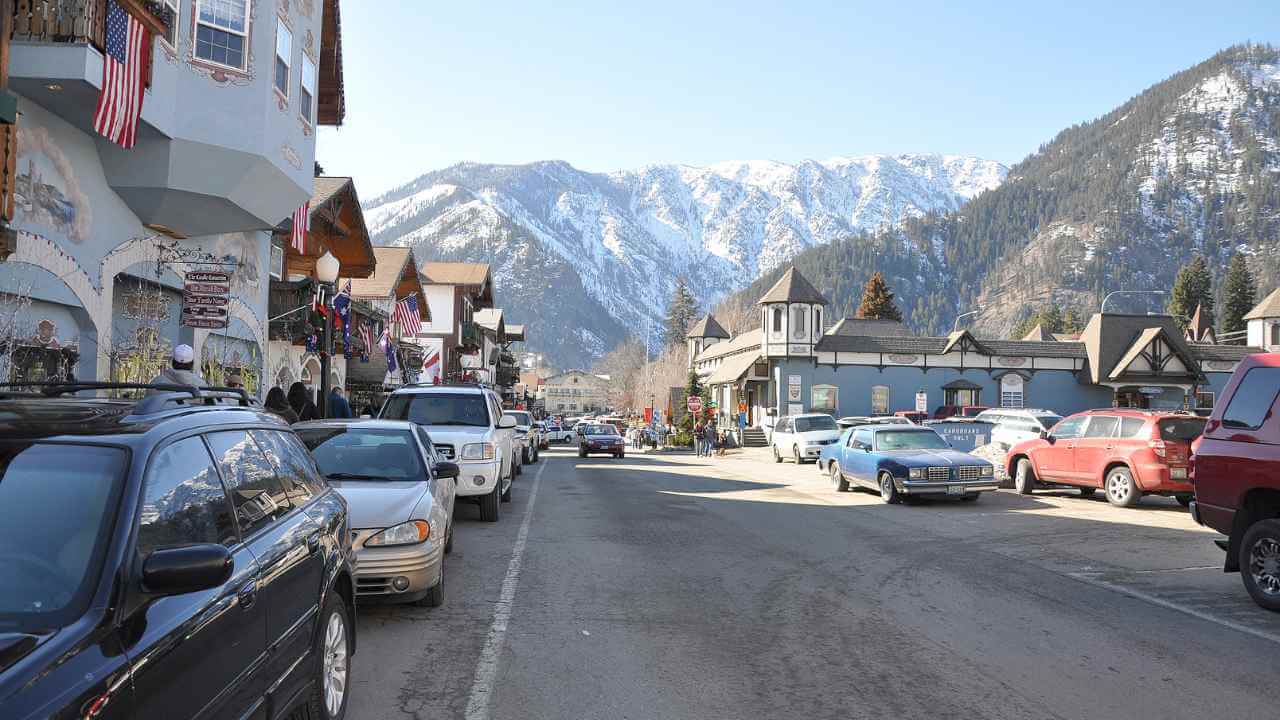 cars are parked on the street in front of a mountain