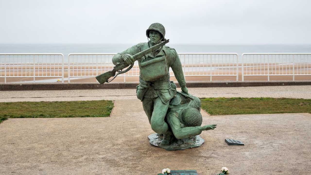 a statue of a soldier holding a rifle on the beach