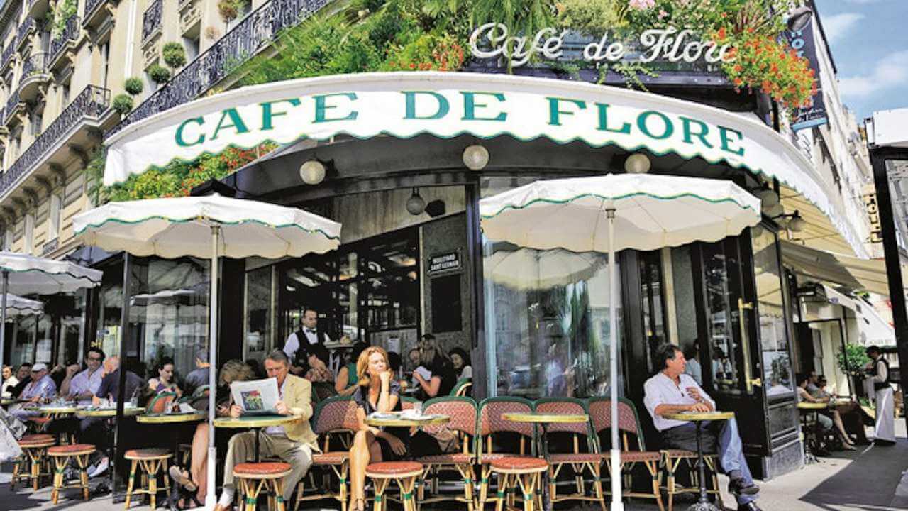 front of flower cafe in paris with people sitting outside at tables