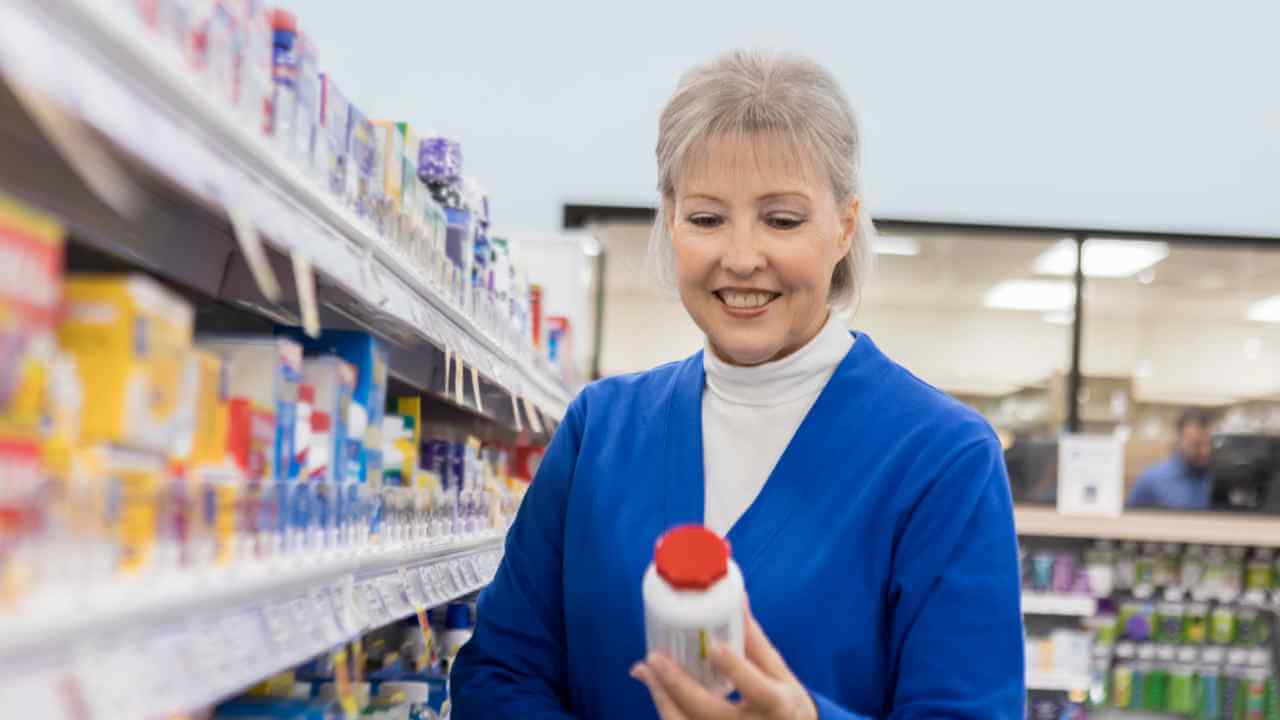 a person in a grocery store holding a bottle of shampoo