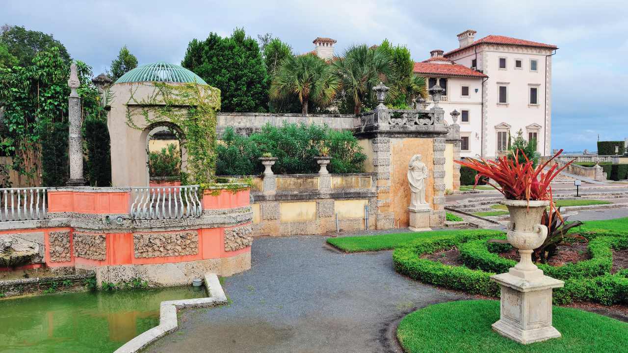 a beautiful garden with a fountain in front of a mansion