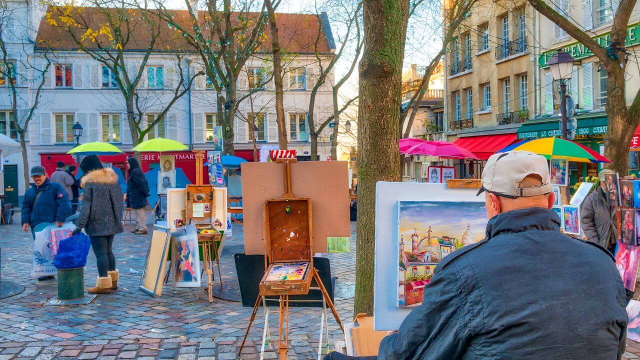 a person is painting on an easel in the middle of an outdoor market